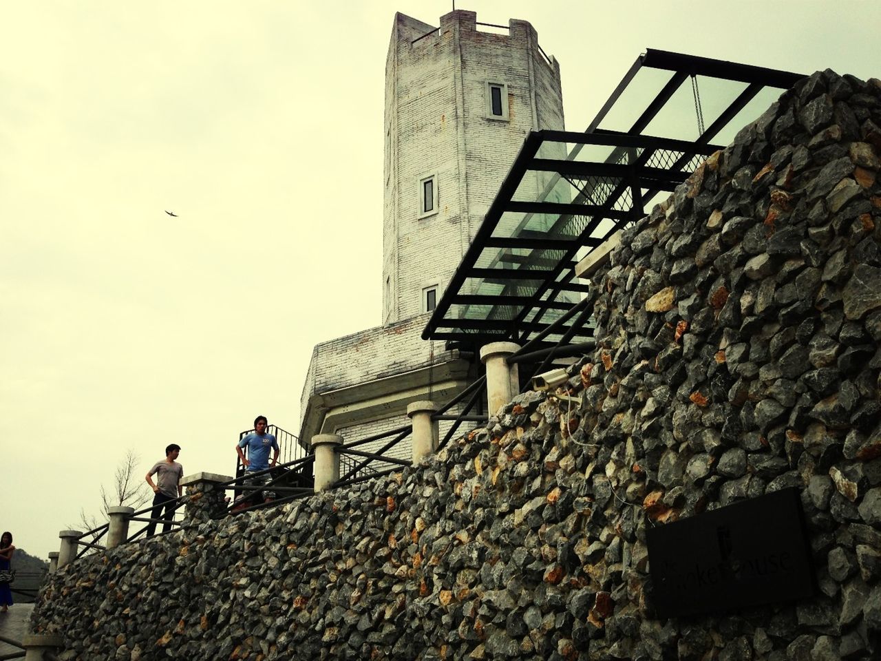 building exterior, architecture, built structure, low angle view, sky, clear sky, roof, stone wall, day, men, rock - object, house, steps, lifestyles, outdoors, stone - object, stone material, building