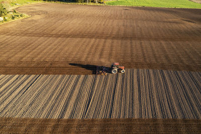 Aerial view of tractor plowing field at sunset