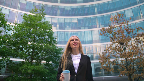 Portrait of young woman standing against trees