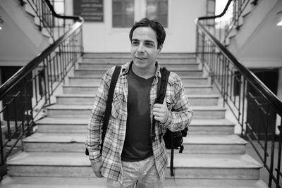 Portrait of young man standing on staircase
