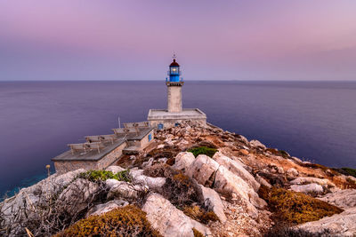 Lighthouse by sea against sky during sunset