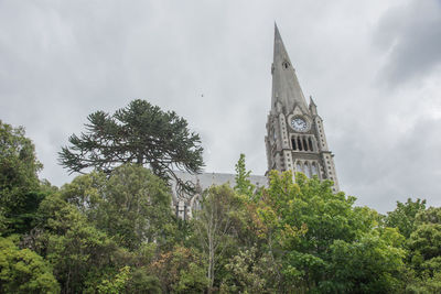 Low angle view of trees and building against sky