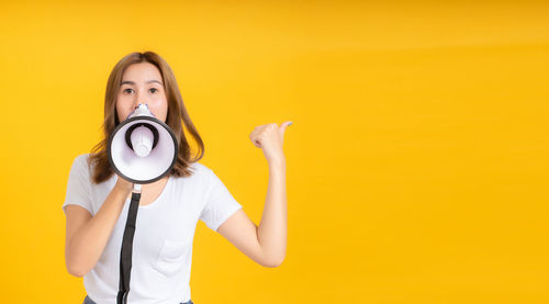 Portrait of young woman holding yellow camera