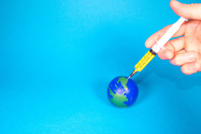 Midsection of person holding ice cream against blue background