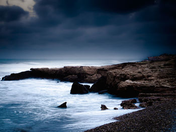 Scenic view of rocks in sea against sky