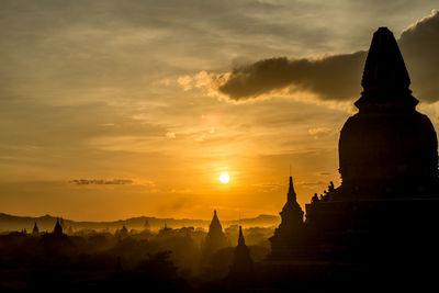 Old silhouette buddhist temples against sky during sunset