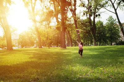 Full length of girl running while flying kite on field