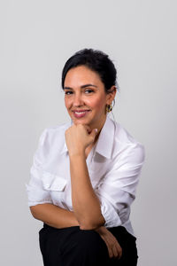 Portrait of young woman standing against white background