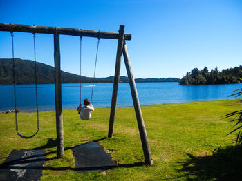 Rear view of baby swinging on swing against clear sky