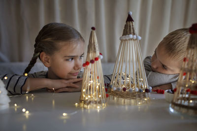 Cute sibling looking at illuminated christmas ornament