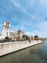 Buildings at waterfront against cloudy sky