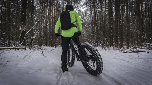 Rear view of person riding bicycle on snow field