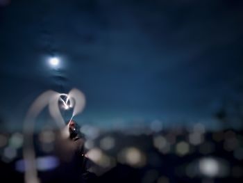 Close-up of hand holding crystal ball against sky at night