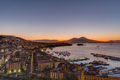 High angle view of river and buildings against sky at sunset