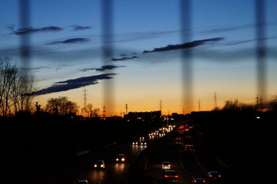 Cars on road in city against sky at sunset