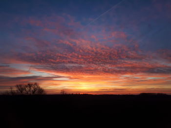 Silhouette landscape against dramatic sky during sunset