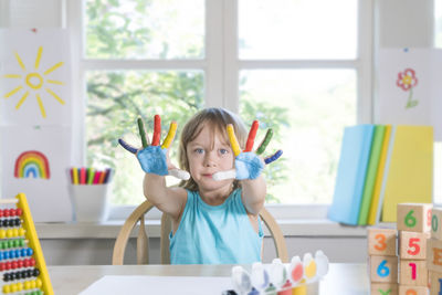 Portrait of happy girl on table against window