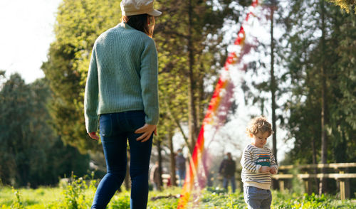 Rear view of mother playing with son at park