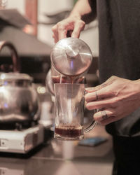 Midsection of man pouring coffee in cup