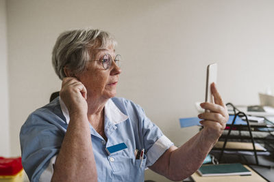 Senior female healthcare worker consulting patient through video call at medical clinic