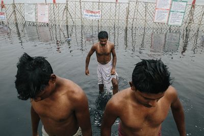 Rear view of shirtless man swimming in water