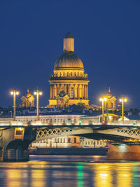 Illuminated bridge and cathedral over river in city 