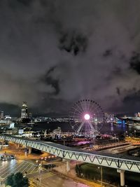 Illuminated bridge over river against sky in city at night