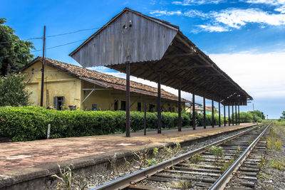 Railroad tracks by old building of fromer station against sky