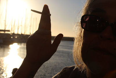 Close-up of woman hand against sky during sunset