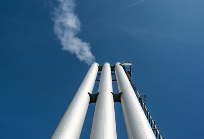 Low angle view of chimneys against blue sky