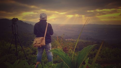 Rear view of man standing against sky during sunset