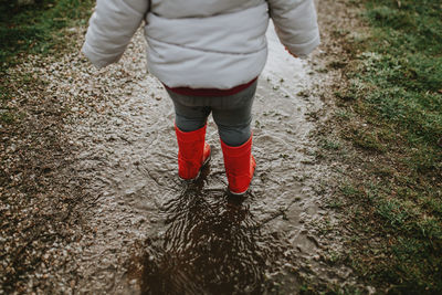 Low section of baby girl standing on puddle during rainy season