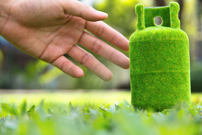 Close-up of hand holding green gas cylinder