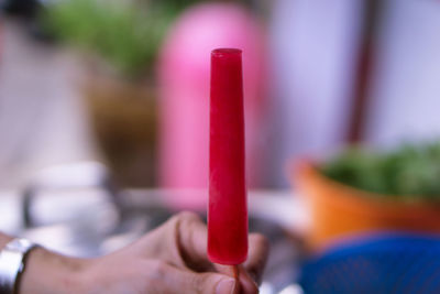Close-up of hand holding red blurred background