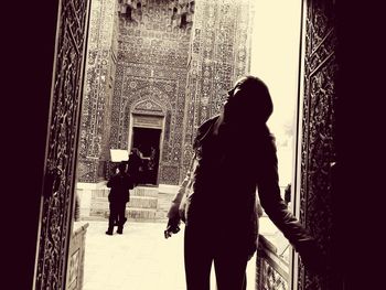 Rear view of woman standing against buildings in city