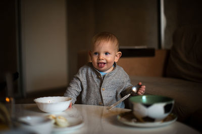 Baby boy sticking out tongue at table