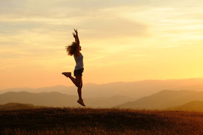 Full length of woman standing on field against sky during sunset