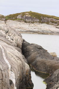 Rock formation on beach against sky