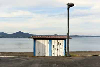 Lifeguard hut on street by sea against sky