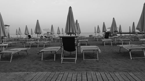 Chairs and tables on beach against clear sky