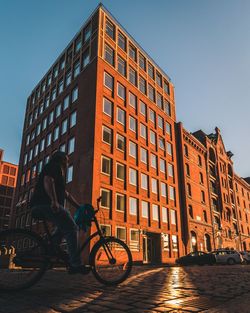 Man riding bicycle on street against buildings in city