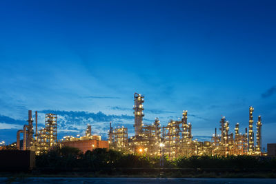 Illuminated factory against blue sky at night