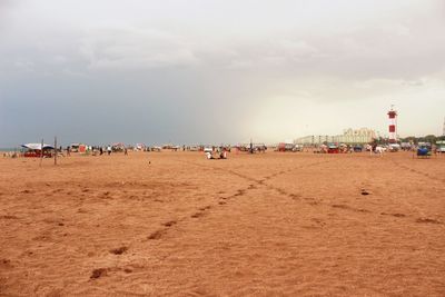 People at sandy beach against cloudy sky