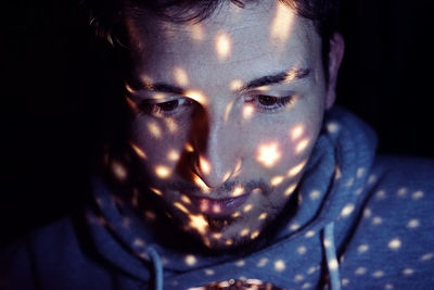 Close-up of man with colorful lights in darkroom