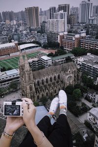 Low section of man photographing buildings in city