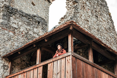 Young woman in winter clothes on wooden balcony of an old medieval castle.