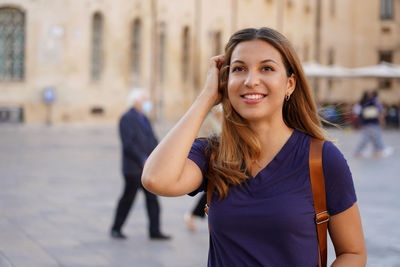 Close up portrait of delightful cheerful latin woman with toothy smile having a walk in foreign city