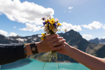 Close-up of hand holding flower against clear sky