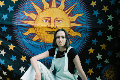 Portrait of young woman standing against blue wall