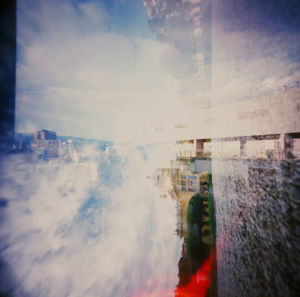 Digital composite image of buildings and sea against sky